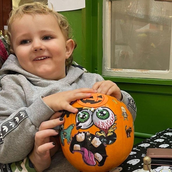Young boy holding pumpkin decorated with stickers